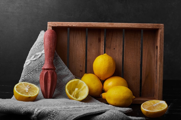 Free Photo lemons isolated on a black wall in a wooden tray.