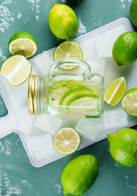 Lemons with ice cubes, lemonade on plaster and cutting board,