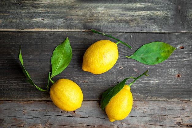 Free Photo lemons with leaves top view on a dark wooden background