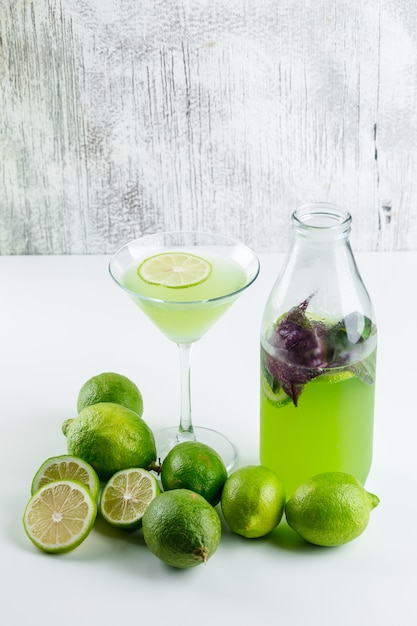 Free photo lemons with lemonade, basil leaves high angle view on white and grungy