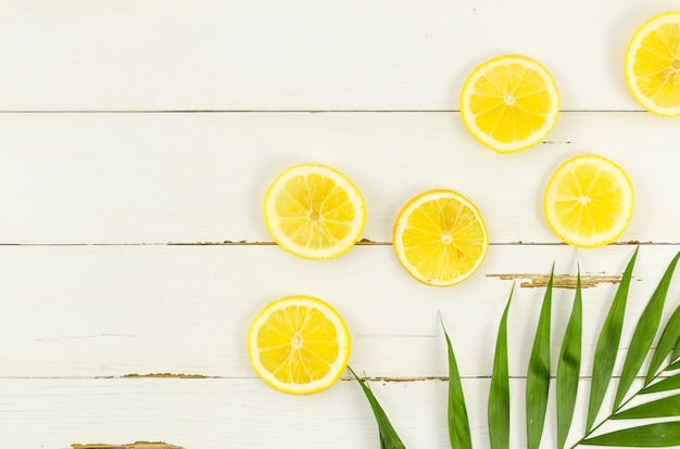 Free photo lemons with palm leaf on table