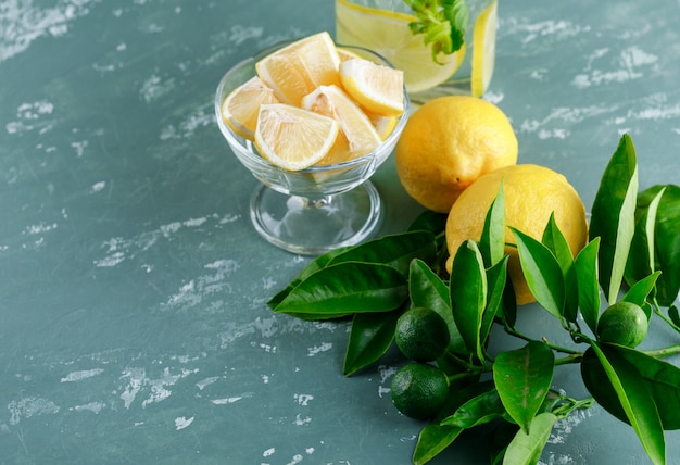 Free photo lemons with slices, leaves, detox water on plaster surface