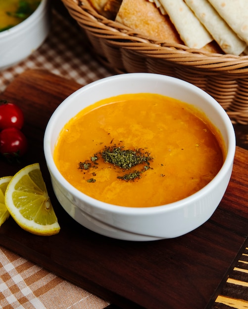 Lentil soup in bowl mint lemon crackers side view