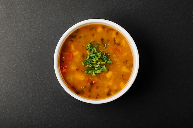 Lentil soup with mixed ingredients and herbs in a white bowl.