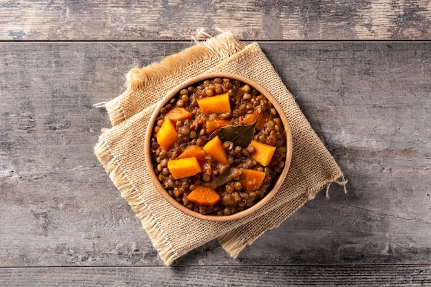 Lentil stew ragout with pumpkin and carrot in bowl on wooden table