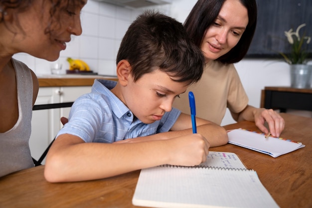 Lesbian couple helping their son to do his homework