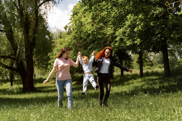 Free photo lesbian couple spending time with their kid in the park