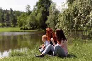 Free photo lesbian couple spending time with their kid in the park