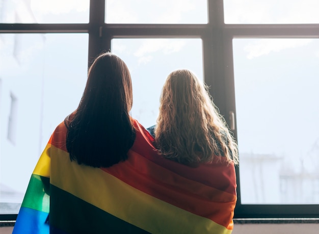 Lesbian sweethearts wrapped in LGBT flag