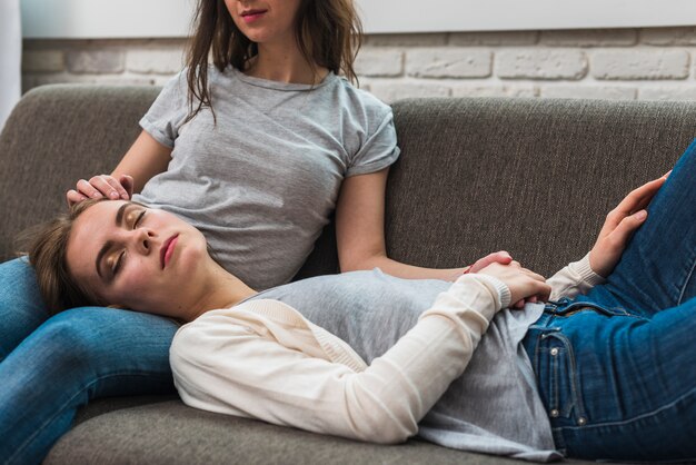 Lesbian young couple relaxing on grey sofa