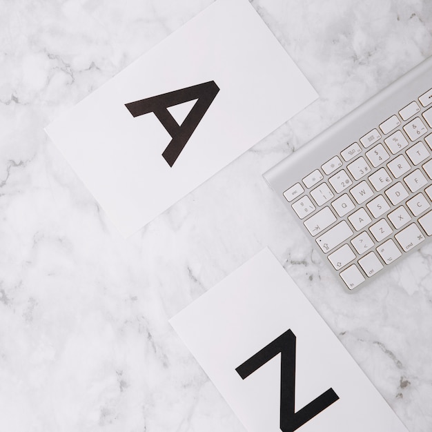 Free photo letter a and z on white paper and keyboard on white marble textured background