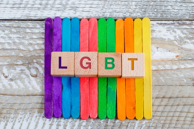 Free photo lgbt concept with colored ice cream sticks, wooden cubes on wooden background flat lay.