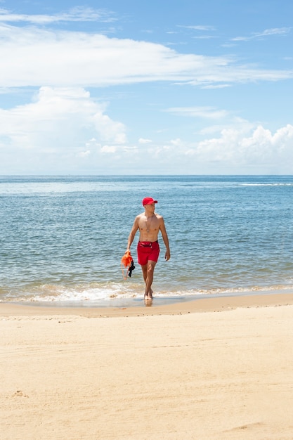 Lifeguard walking on beach full shot