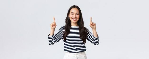 Lifestyle beauty and fashion people emotions concept Cheerful goodlooking female model pointing fingers up to shop promotion banner smiling camera recommend click link to online store