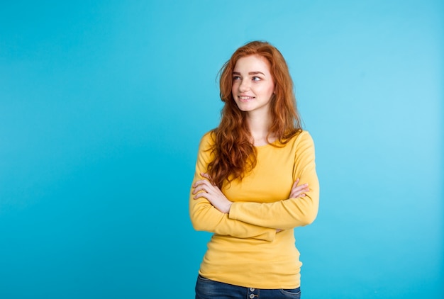 Lifestyle concept - Close up Portrait young beautiful attractive ginger red hair girl playing with her hair with shyness. Blue Pastel Background. Copy space.