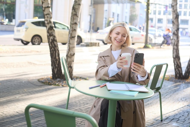 Free Photo lifestyle portrait of young woman has video conversation chatting on smartphone app showing takeaway