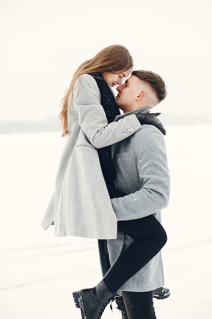 Lifestyle shot of couple walking in snowy forest. People spending winter vacation outdoors.