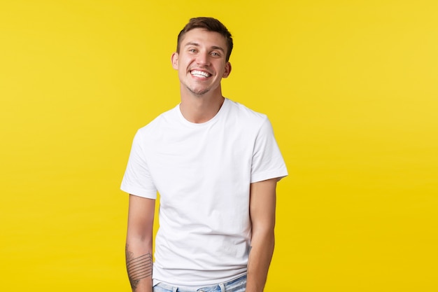 Free Photo lifestyle, summer and people emotions concept. handsome charismatic caucasian guy in casual white t-shirt smiling broadly with perfect white smile, standing joyful yellow background.