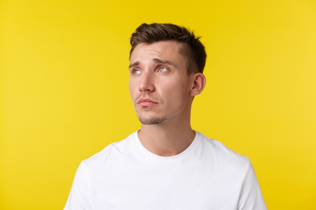 Lifestyle, summer and people emotions concept. Portrait of tired and distressed young man, looking upper left corner with exhausted expression, feeling depression or loneliness.