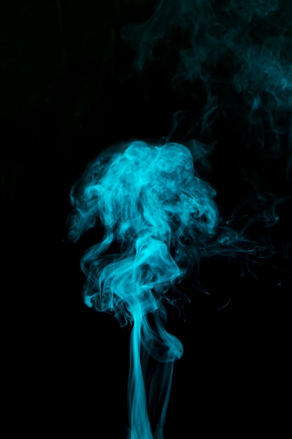 Free photo light blue smoke blowing against black background