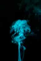 Free photo light blue smoke blowing against black background