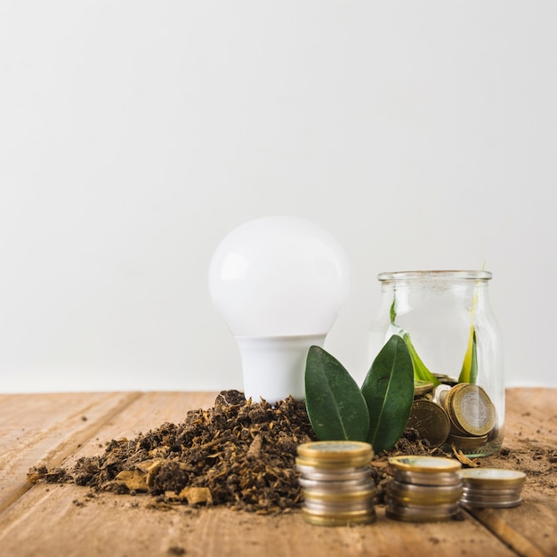 Free Photo light bulb with glass jar and coins stacks