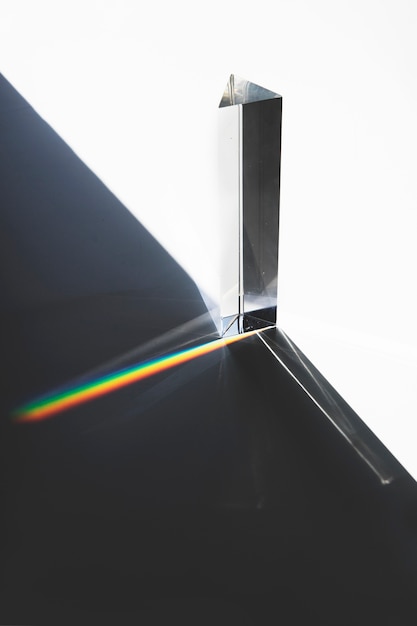 Free photo light passing through a triangular prism with dark shadow on white surface