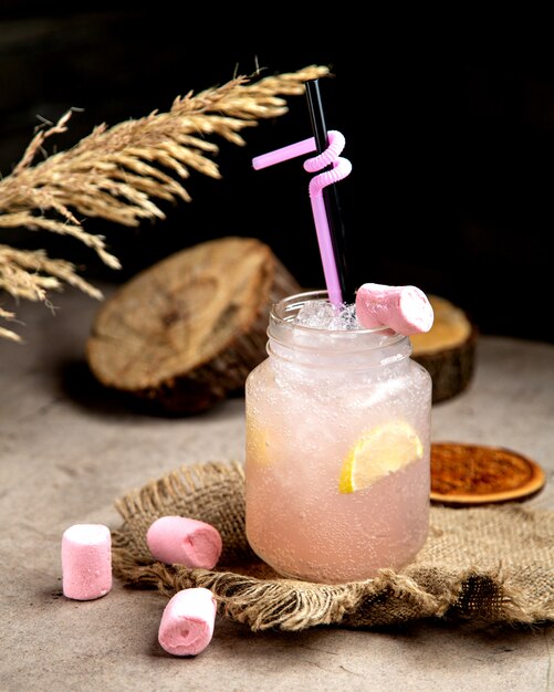 Light pink fizzy drink with lemon slice garnished with marshmellow