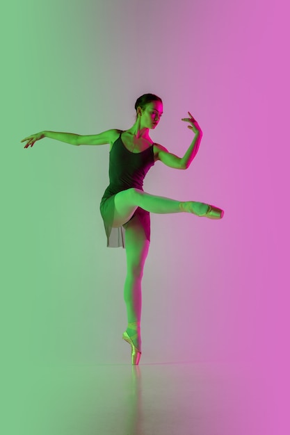 Free photo light. young and graceful ballet dancer isolated on gradient pink-green  wall in neon. art, motion, action, flexibility, inspiration concept. flexible ballerina, weightless jumps.