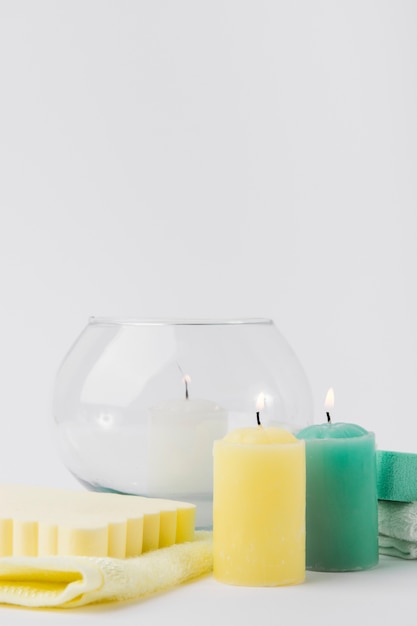 Lighted colorful candles with sponge and napkin against white backdrop