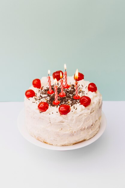 Lighted striped candles on white cake against dual backdrop