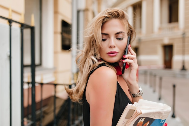 Lightly-tanned female model with long blonde hair listening someone on phone with eyes closed