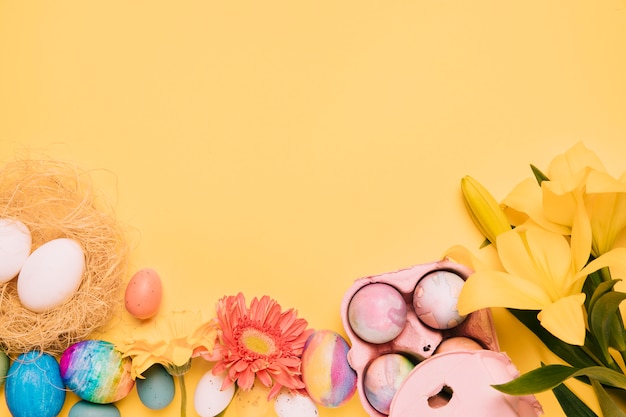 Free photo lily; gerbera flower with easter eggs on yellow background