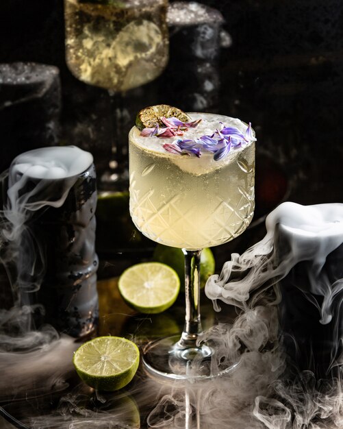 Lime cocktail garnished with lime and flower petals in long stem glass