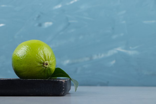 Free photo lime fruit with leaves on cutting board.