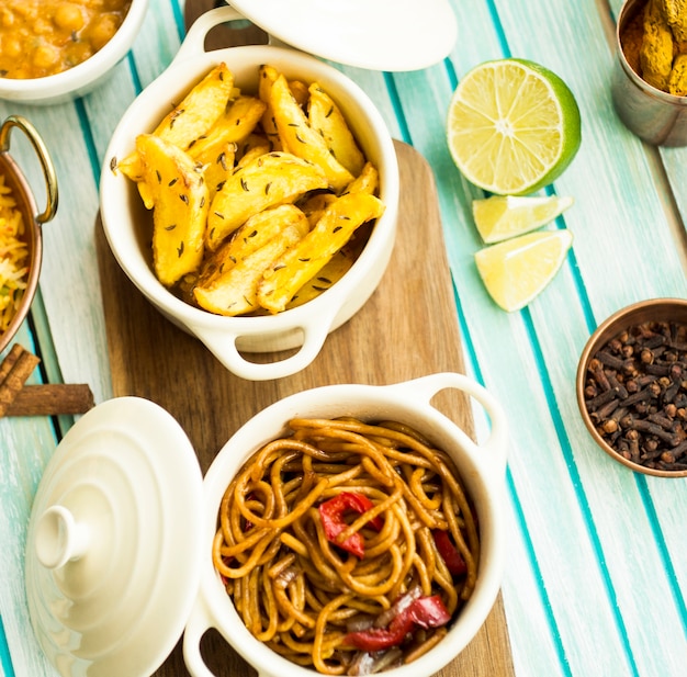 Lime and spices near fried potatoes and pasta