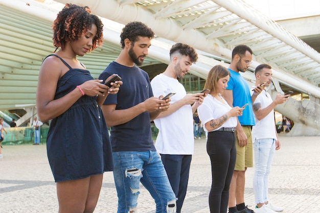 Line of people browsing internet on smartphones outside