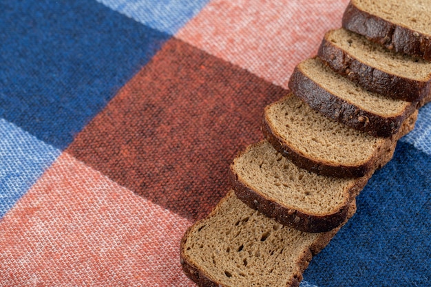 A line of slices of brown bread on a tablecloth .