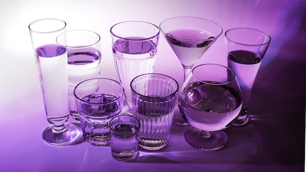 Liquid in different type of glasses on purple background