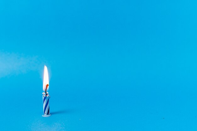 Lit candle on blue background