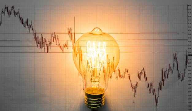 Lit light bulb with graph background