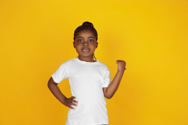 Little african-american girl's portrait isolated on yellow studio