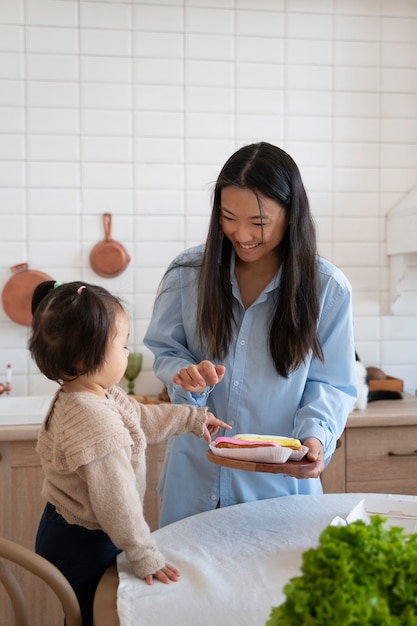 Little asian girl spending at home in the kitchen with her mother