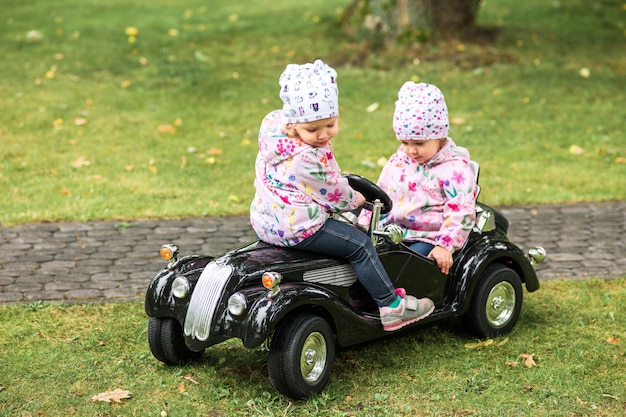 Free photo the little baby girl playing at car against green grass