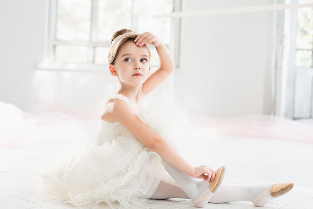 little balerina in white tutu in class at ballet school