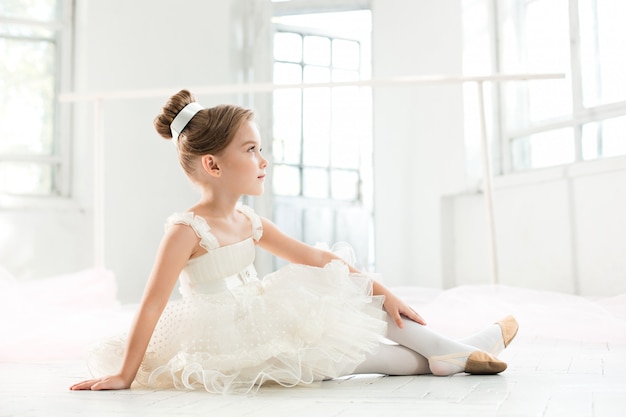 little balerina in white tutu in class at ballet school