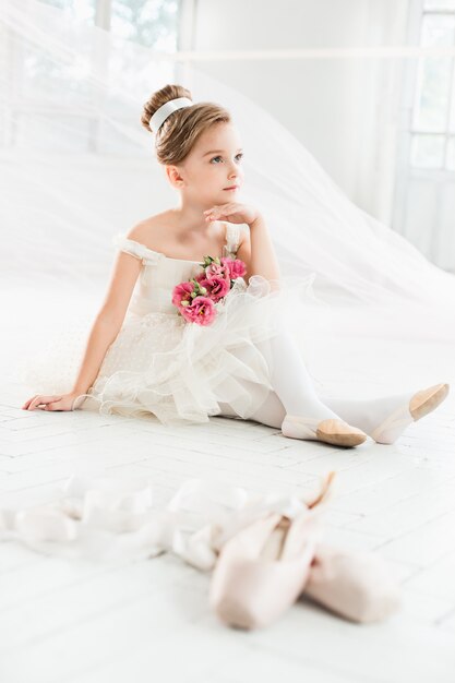 The little balerina in white tutu in class at the ballet