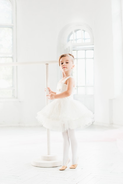 Little ballerina girl in a tutu. Adorable child dancing classical ballet in a white studio.