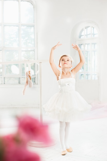 Free photo little ballerina girl in a tutu. adorable child dancing classical ballet in a white studio.