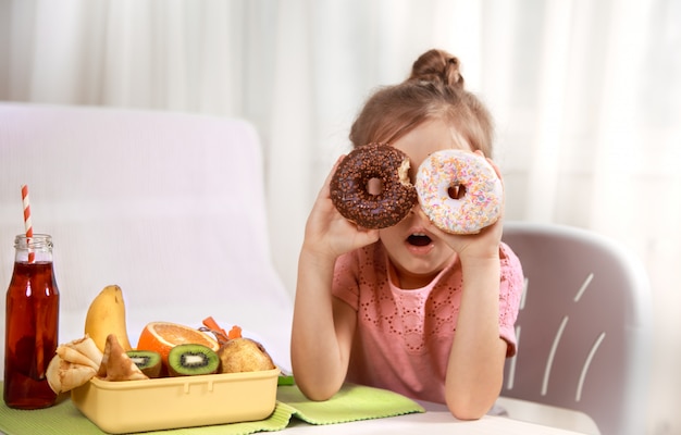 Little beautiful cheerful girl eating a donut